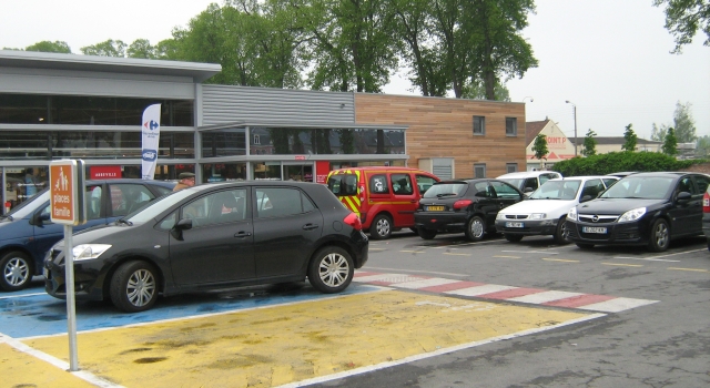 a car park with cars outside a french supermarket